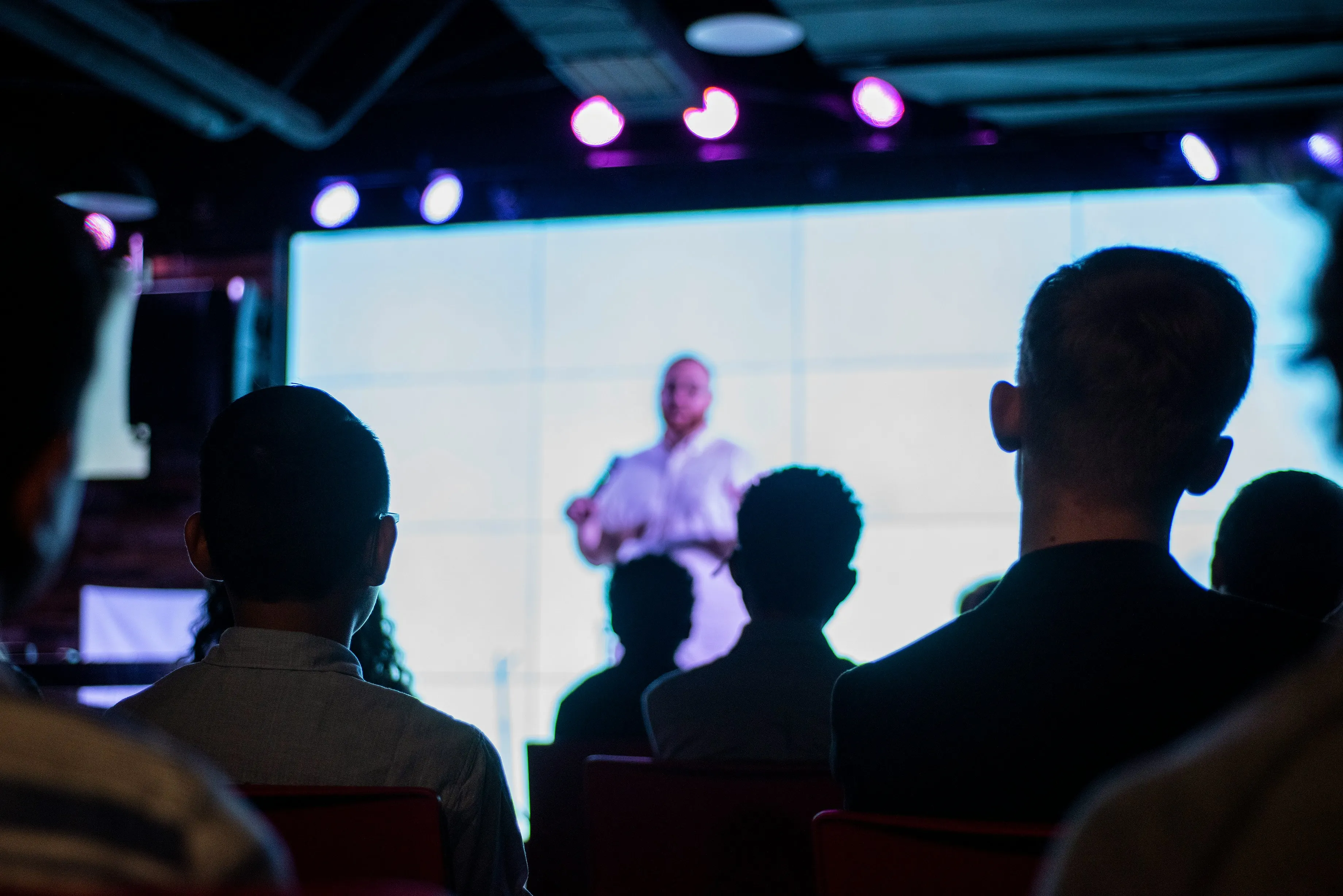 Presenter on stage facing an attentive audience